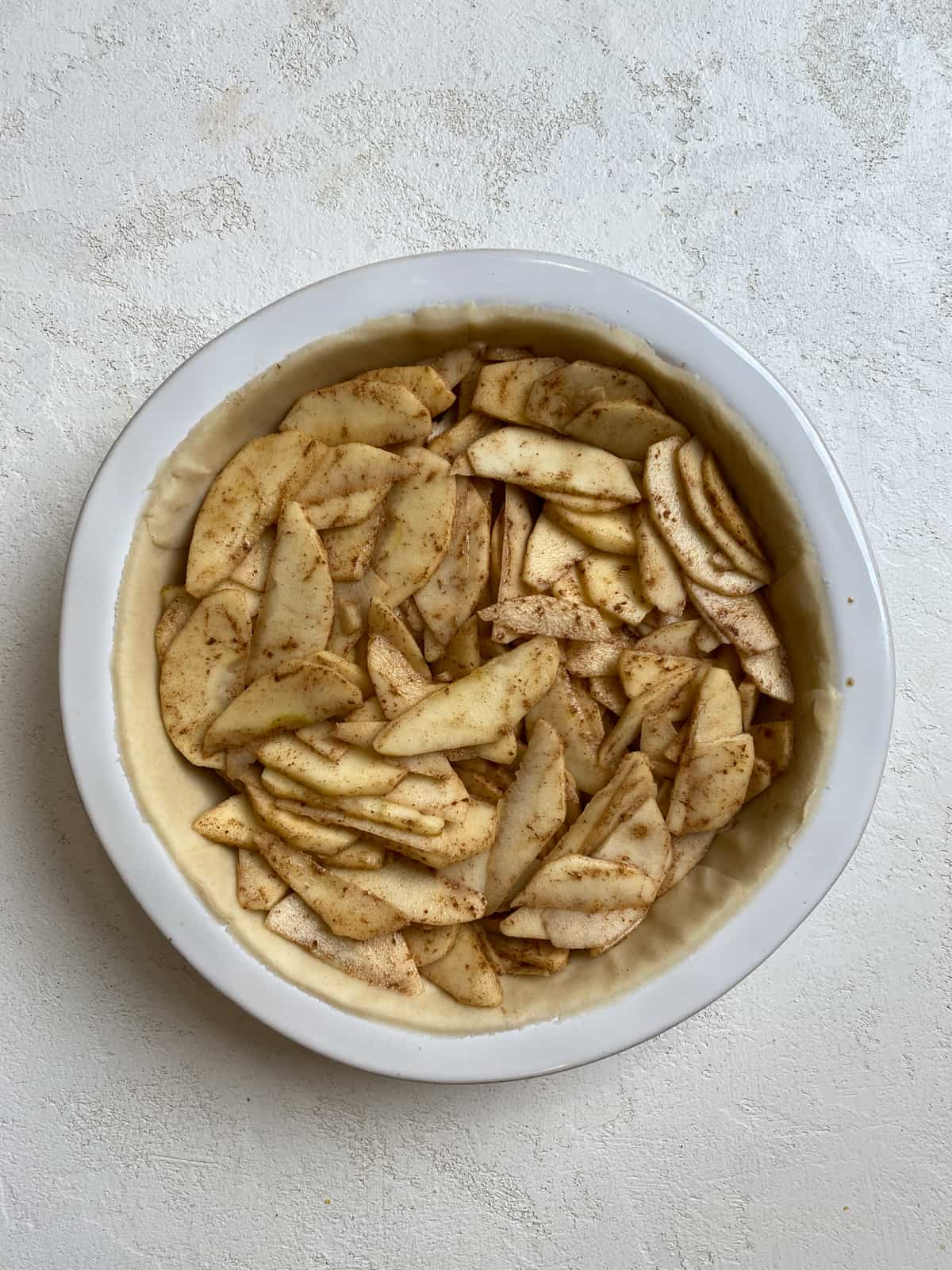 process shot of Easy Apple Pear Pie ingredients in a pie crust against a white surface