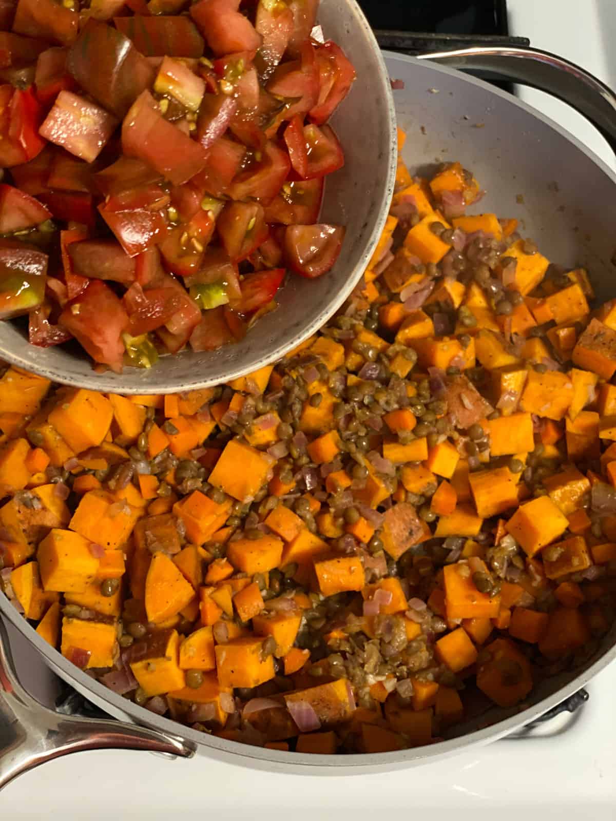 process shot of adding chopped tomatoes to pan