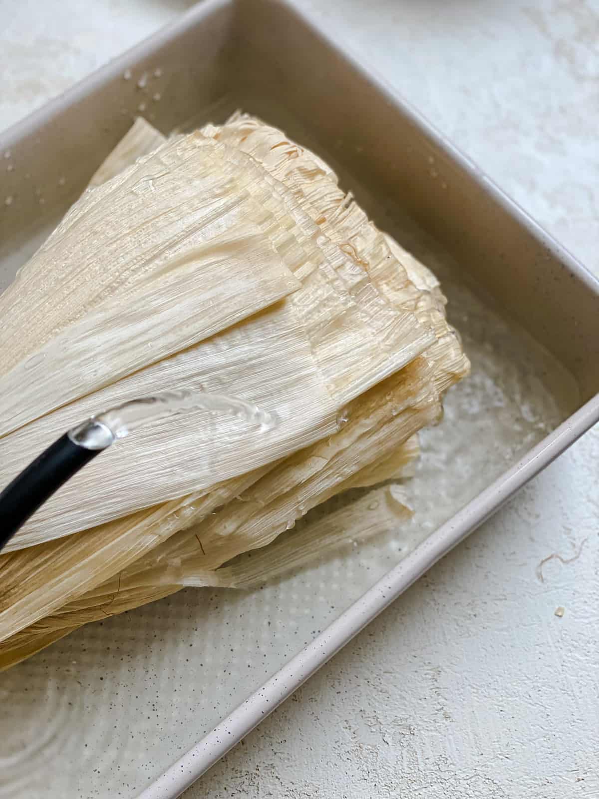 process shot showing corn husk in a baking dish