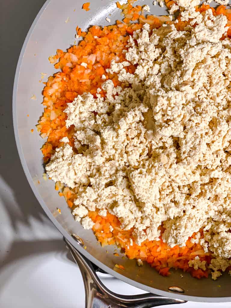 process shot of adding crushed tofu to pan