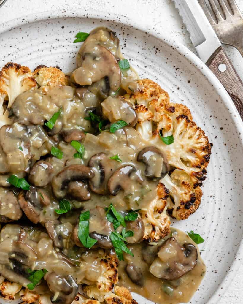 completed Cauliflower Steaks plated on a white plate against a white background