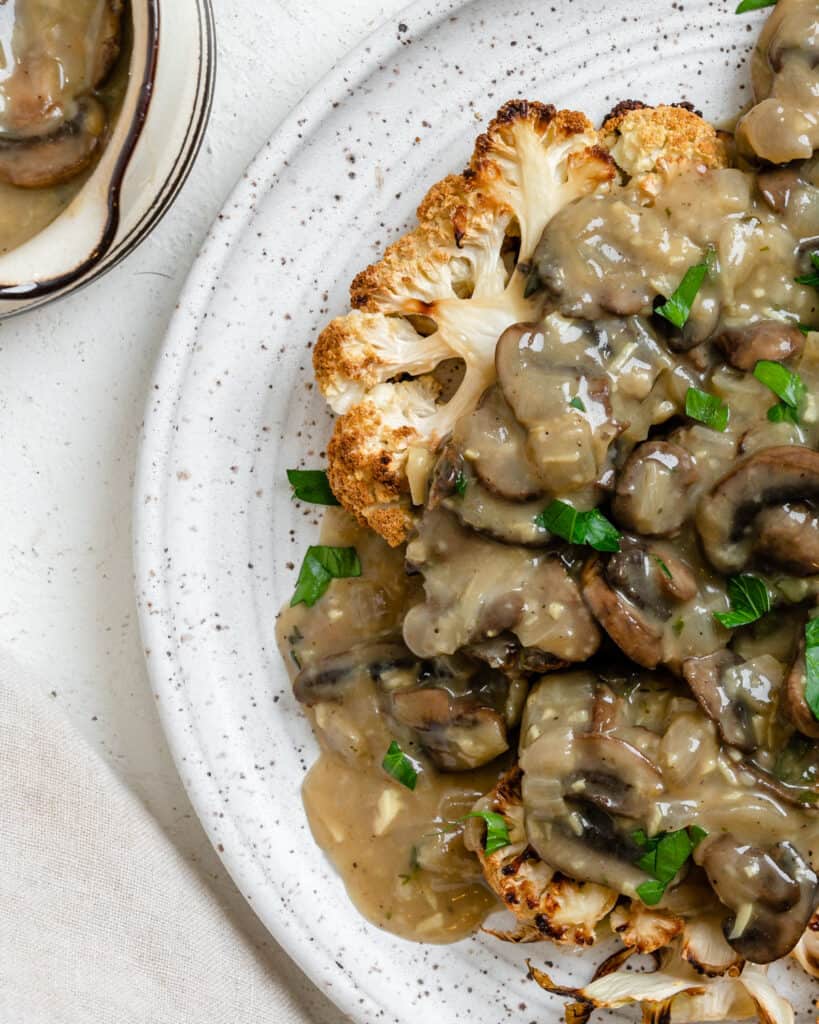 completed Cauliflower Steaks plated on a white plate against a white background