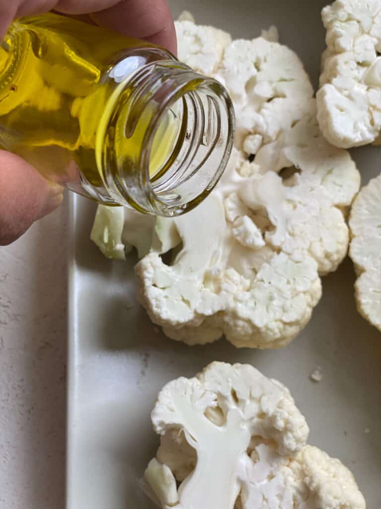 process shot of oil being spread onto cauliflower slices