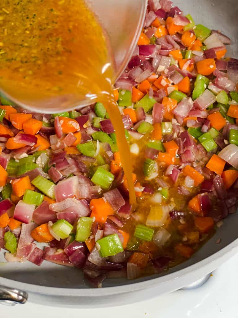 process shot of adding broth to pan