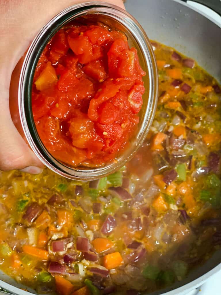 process shot of adding tomatoes to pan