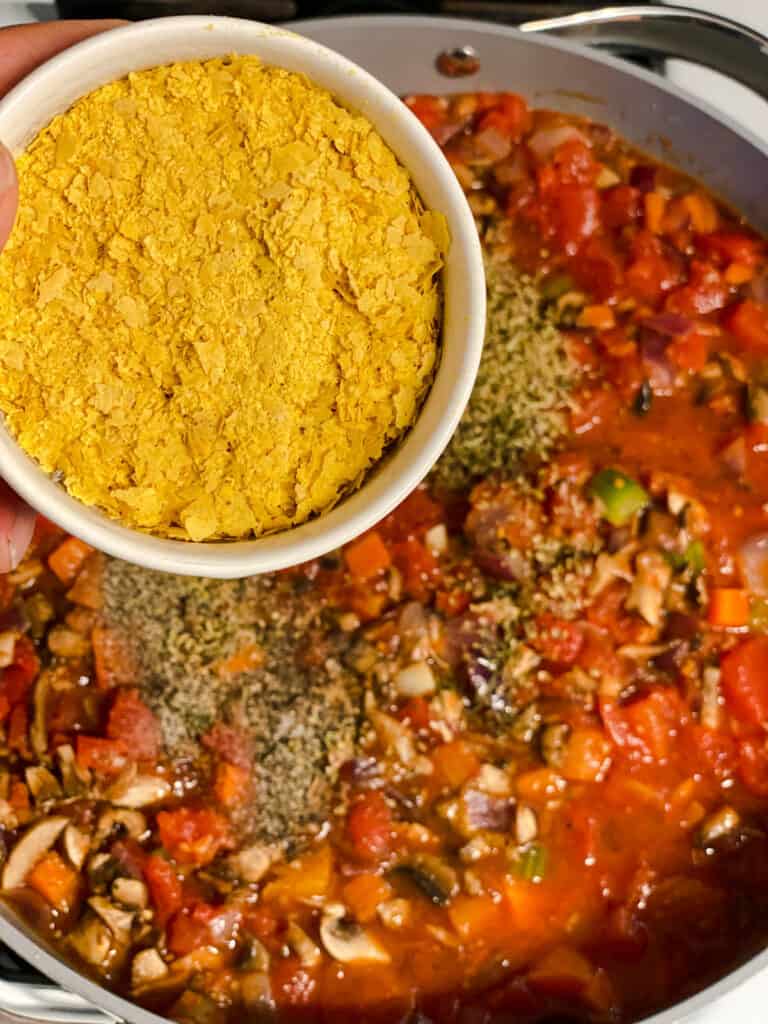 process shot of adding nutritional yeast to pan