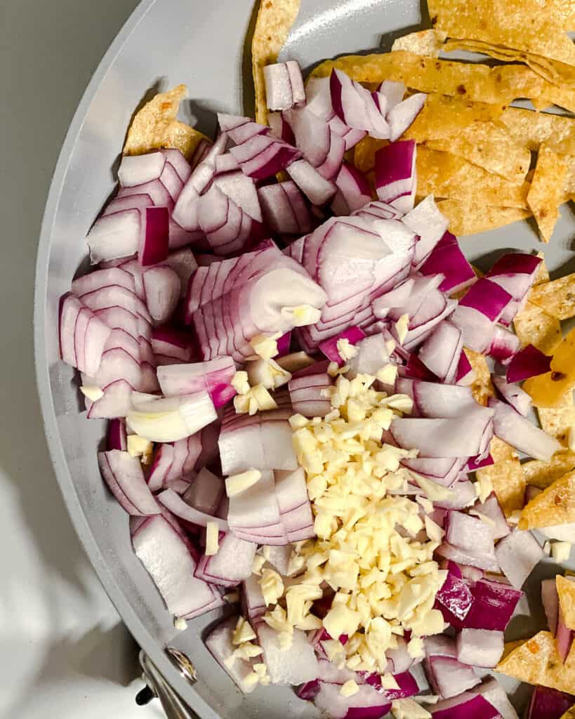 process shot of adding onions and garlic to pan