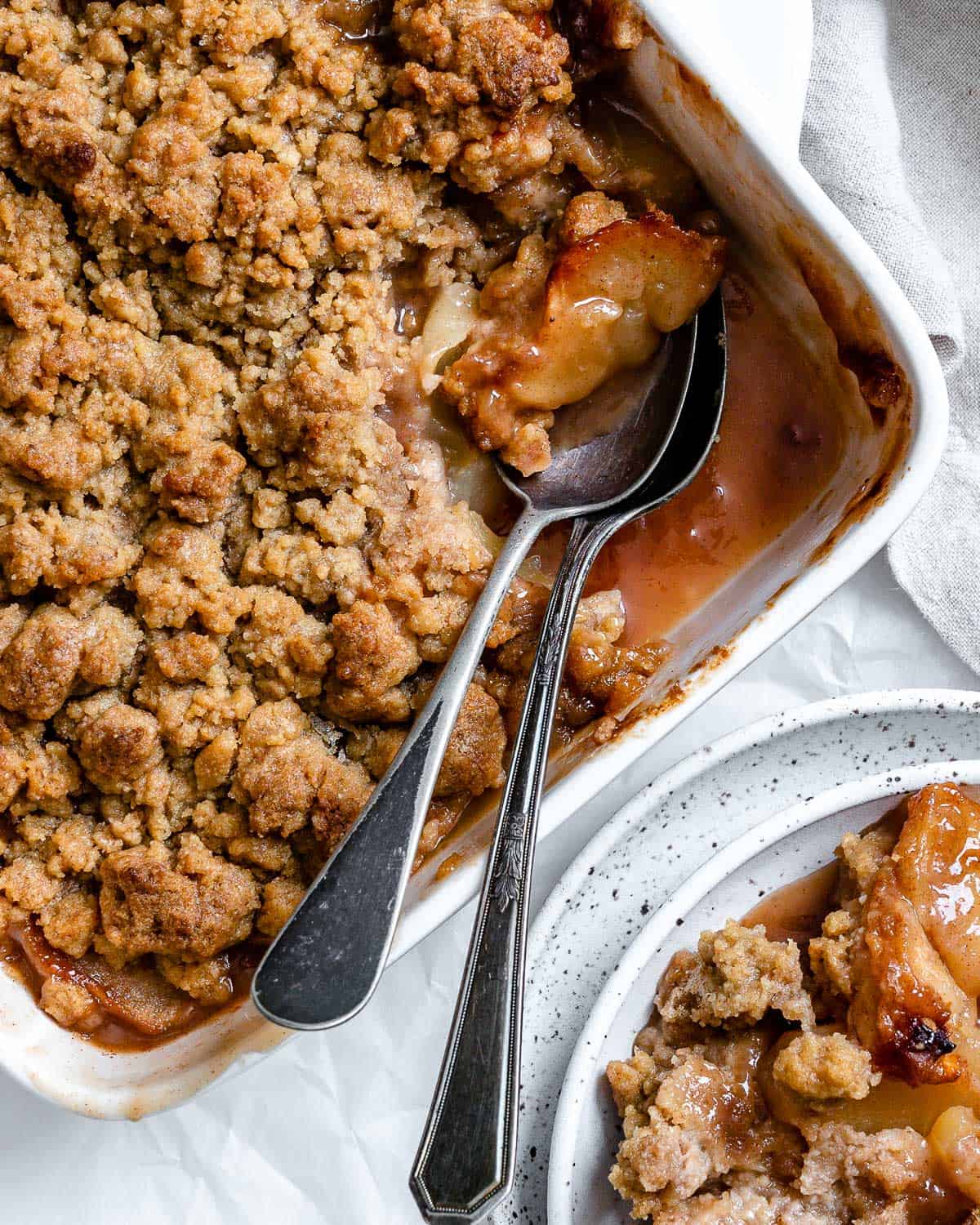 completed Vegan Apple Crumble with a piece missing in a baking dish