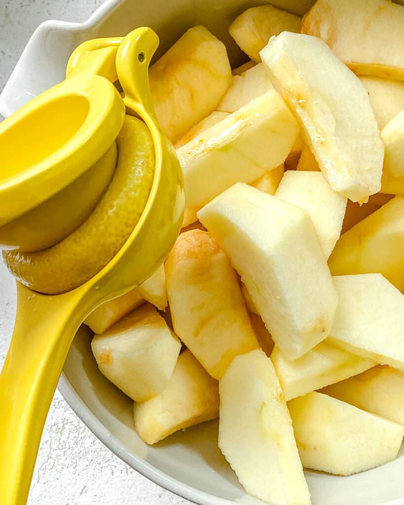 process shot of lemon being pressed onto apples