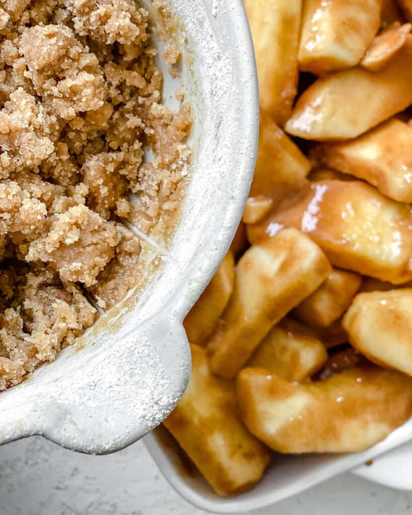 process shot of crumble being added to apples