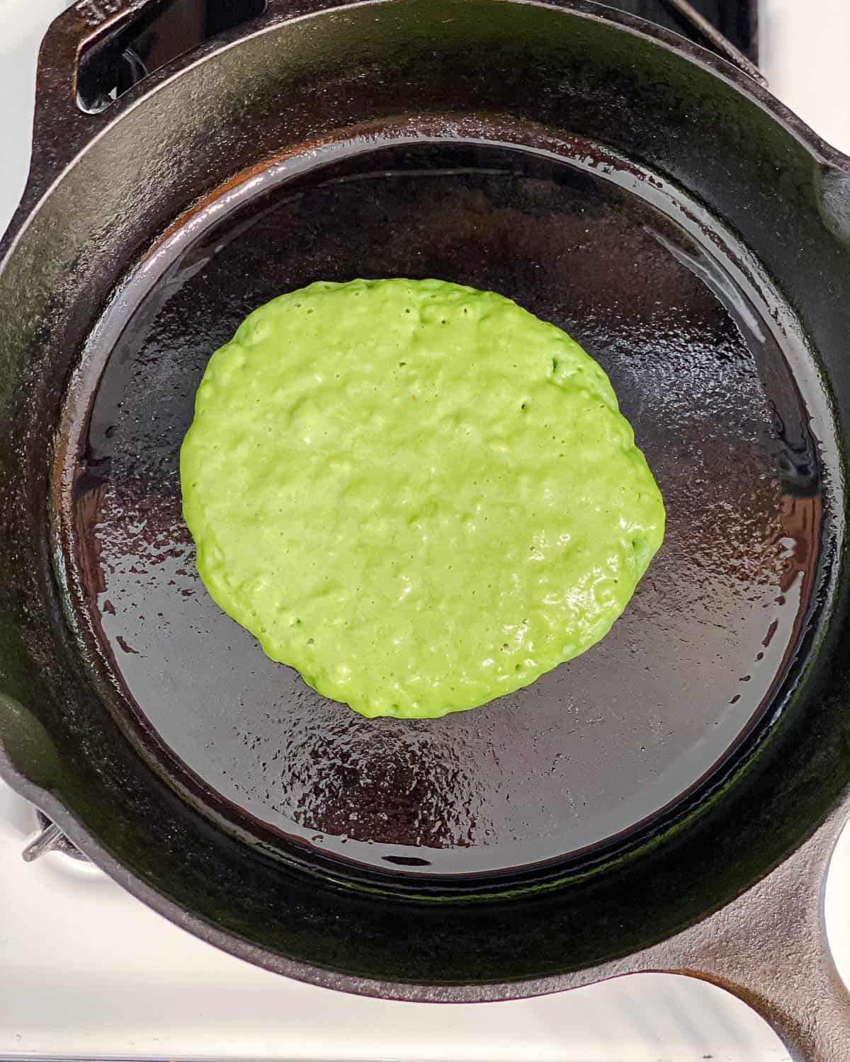 process shot of adding Easy Banana Spinach Pancakes batter to pan