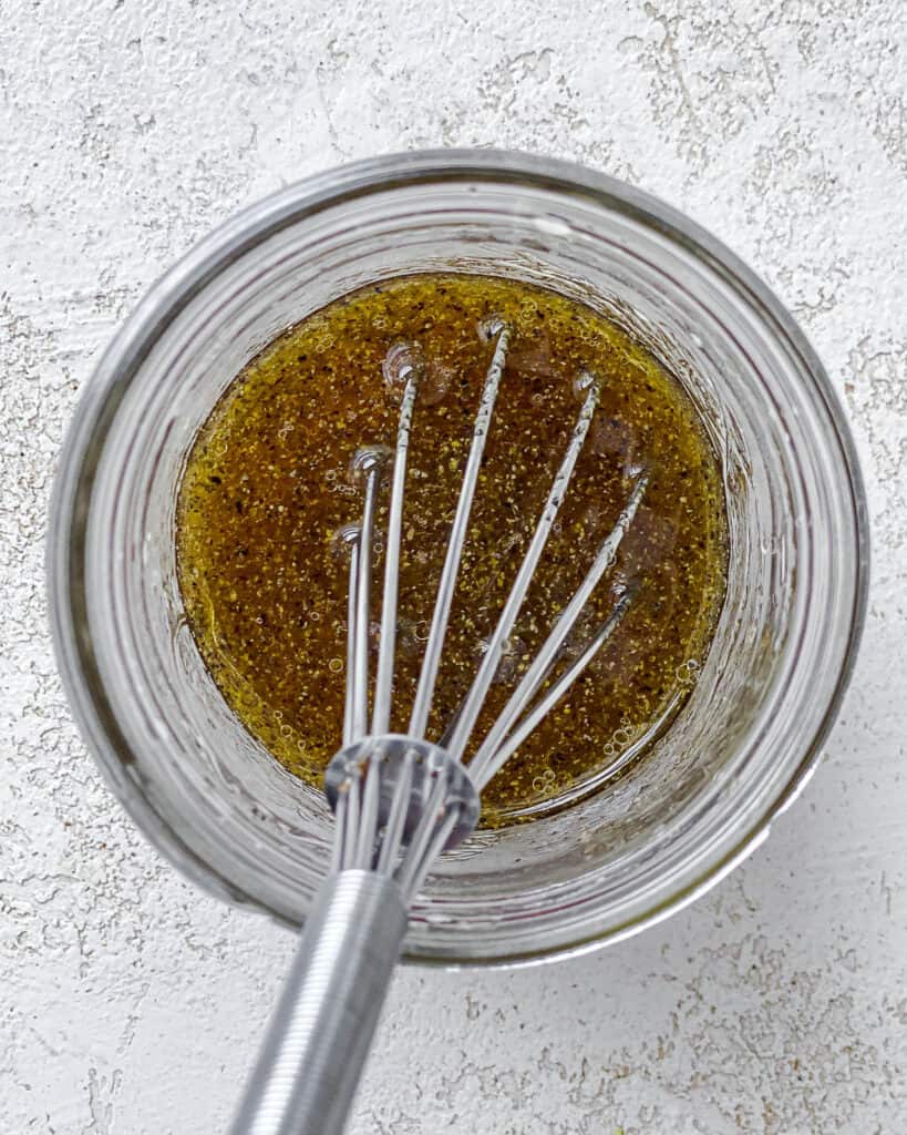 process shot of mixing salad dressing ingredients together in a bowl