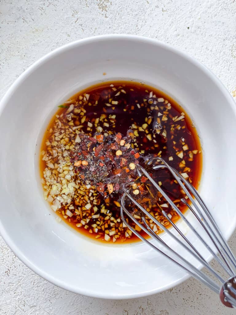 process shot of whisking Spicy Asian Cucumber Salad dressing in a white bowl