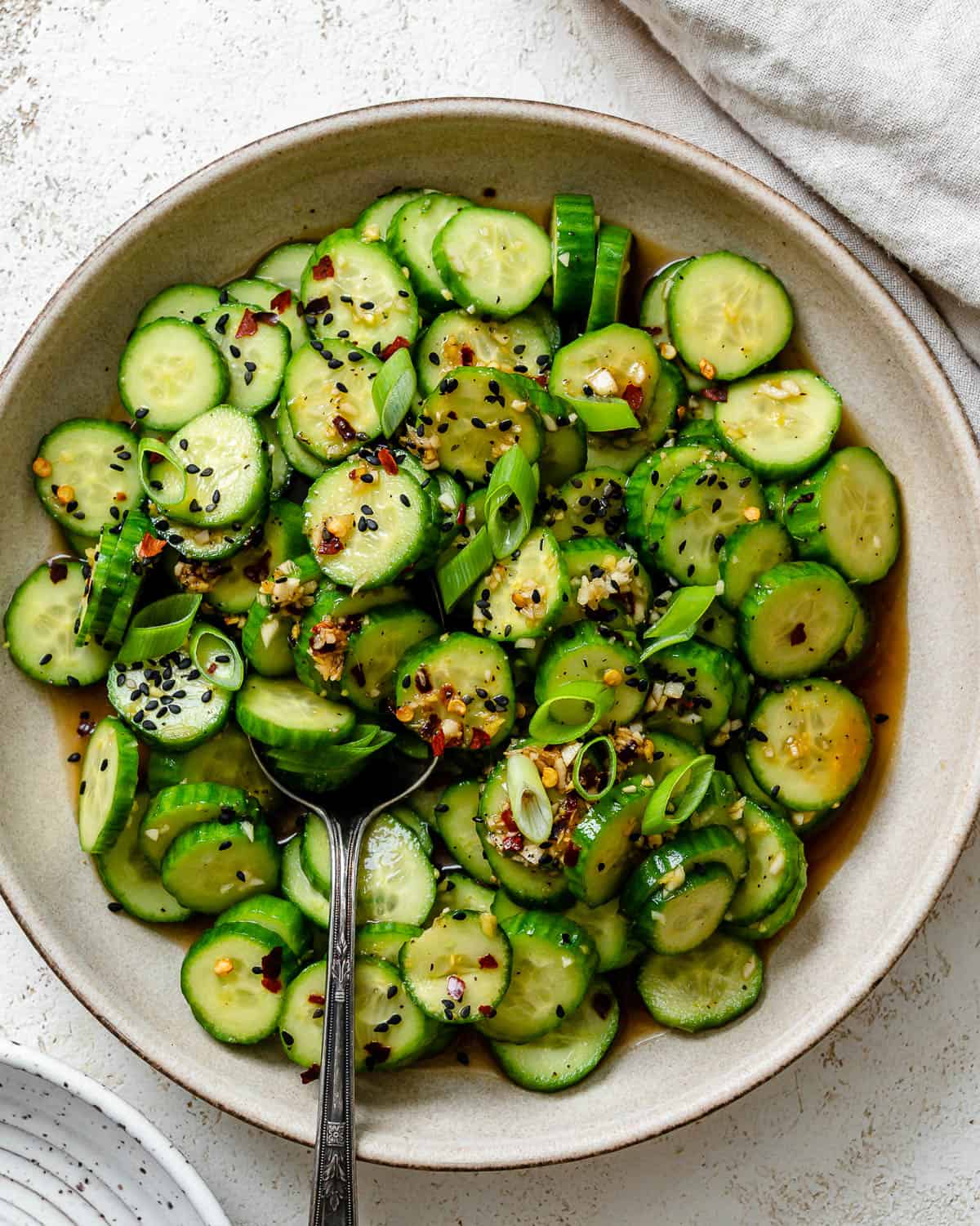 completed Spicy Asian Cucumber Salad plated on a white plate against a white background