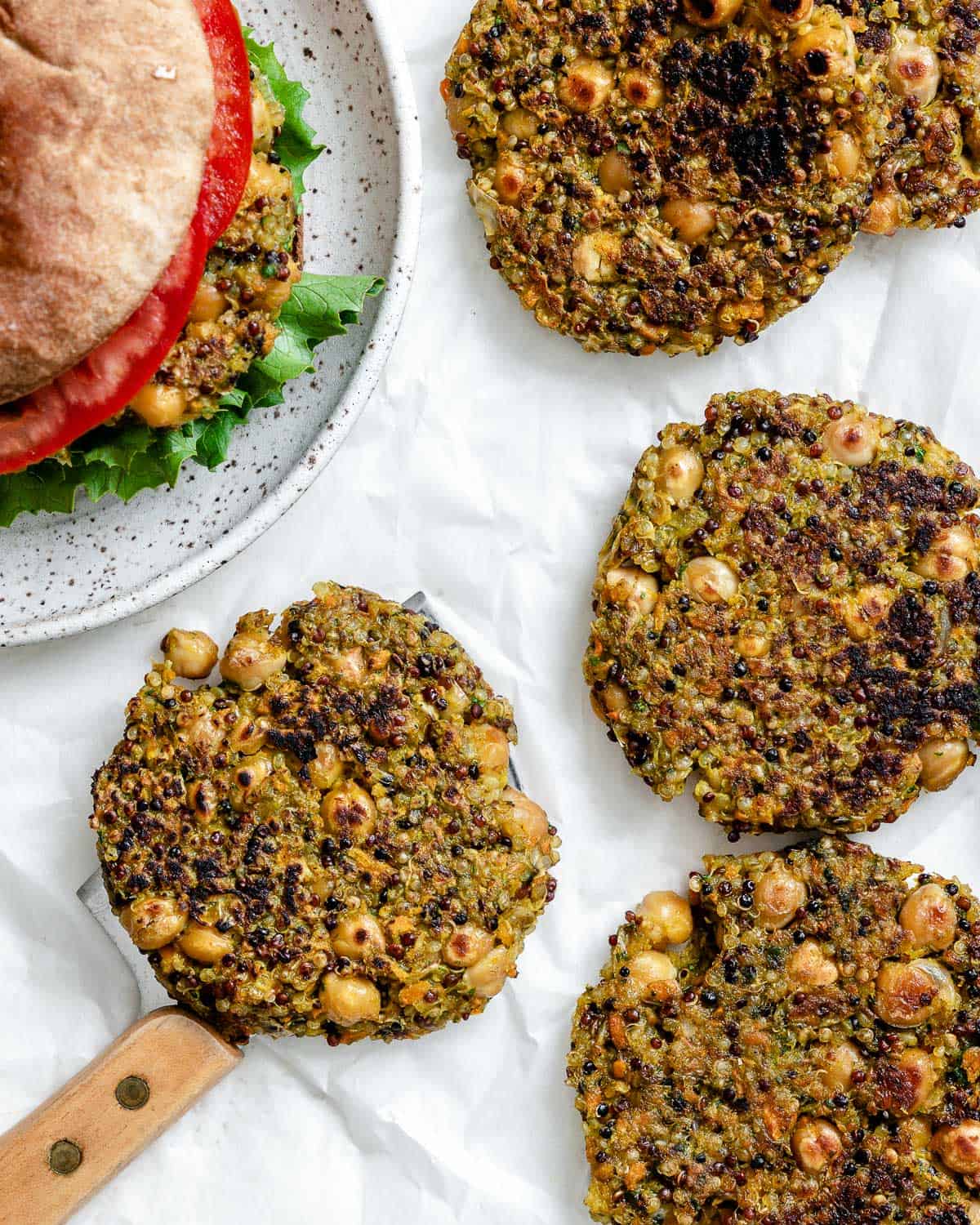 completed Quinoa Chickpea Patties on a white surface alongside a burger