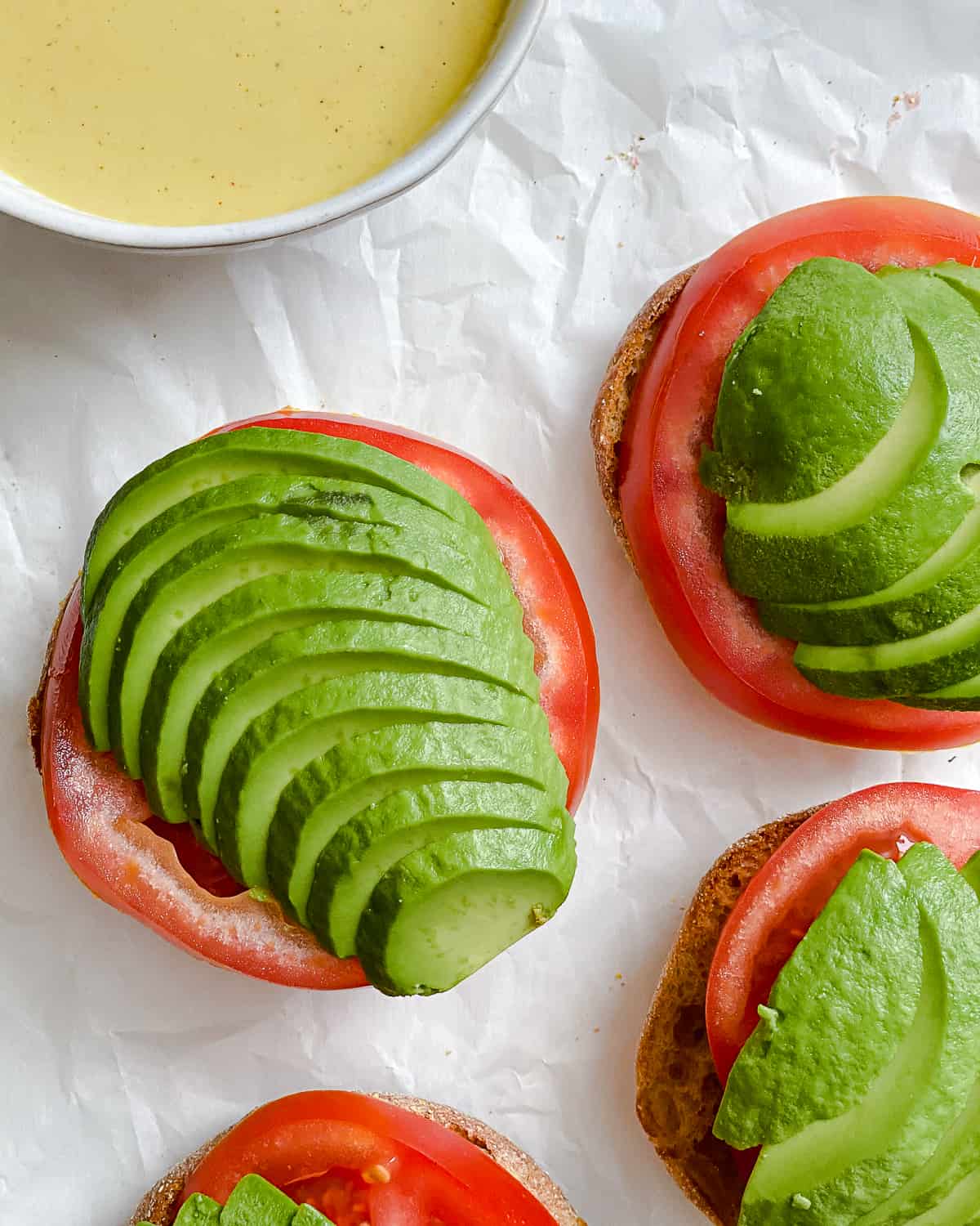 process shot of adding tomato and avocado slices to sandwich