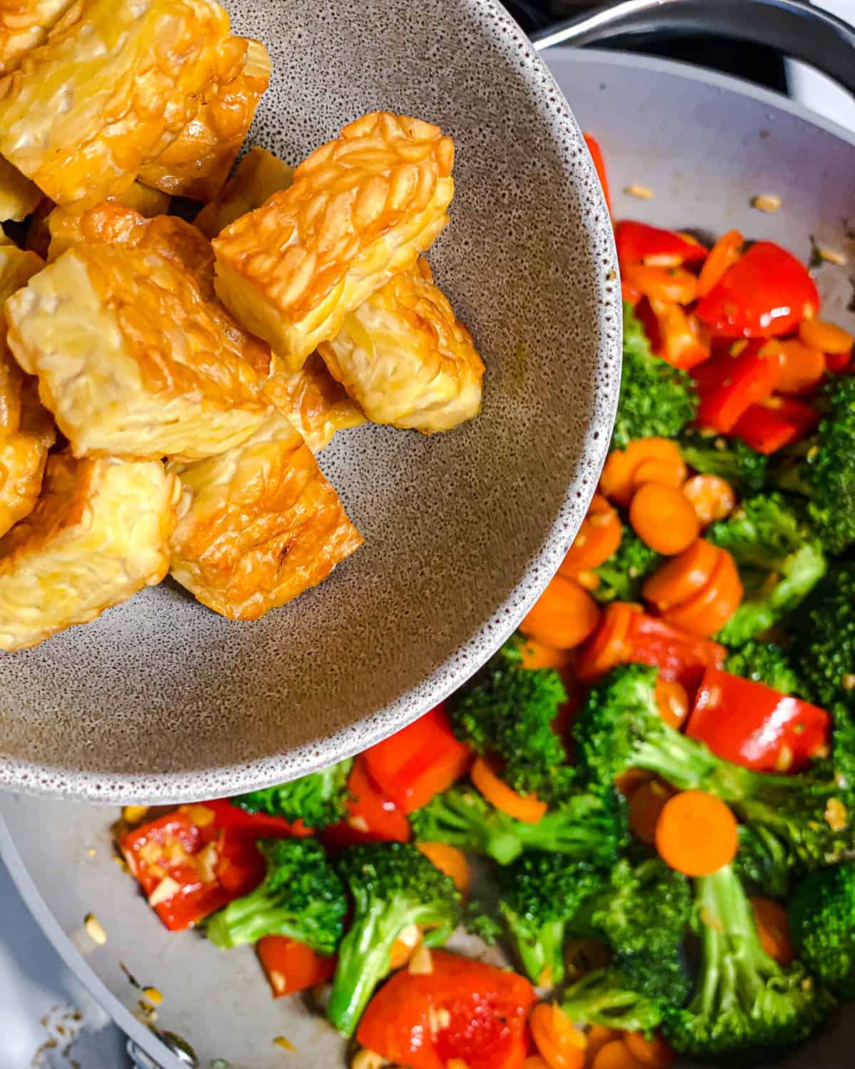 process shot of adding tempeh to pan of veggies