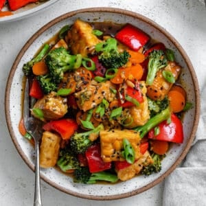 completed Easy Tempeh Stir-Fry plated on a white plate against a white surface