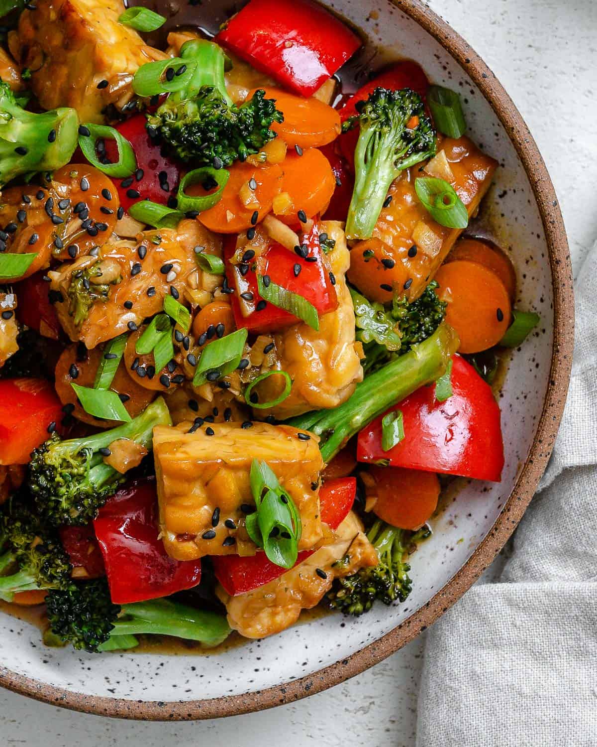 completed Easy Tempeh Stir-Fry plated on a white plate against a white surface