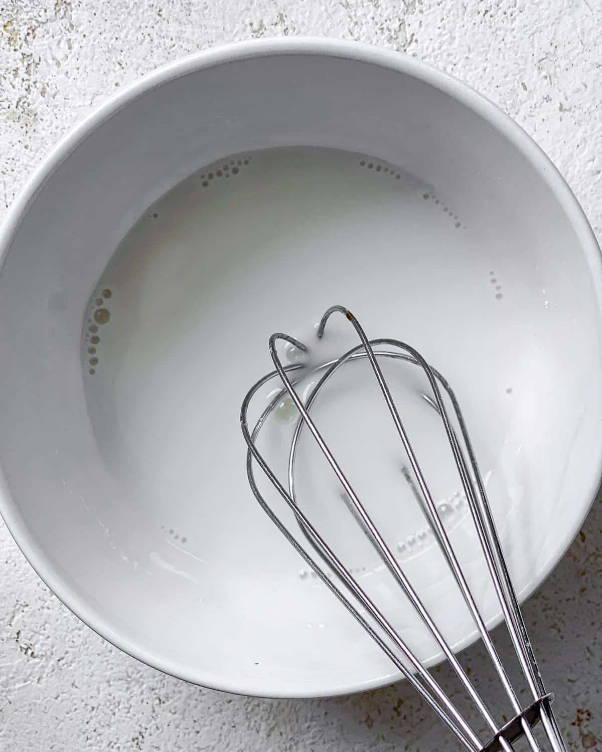 process shot of whisking ingredients in a white bowl