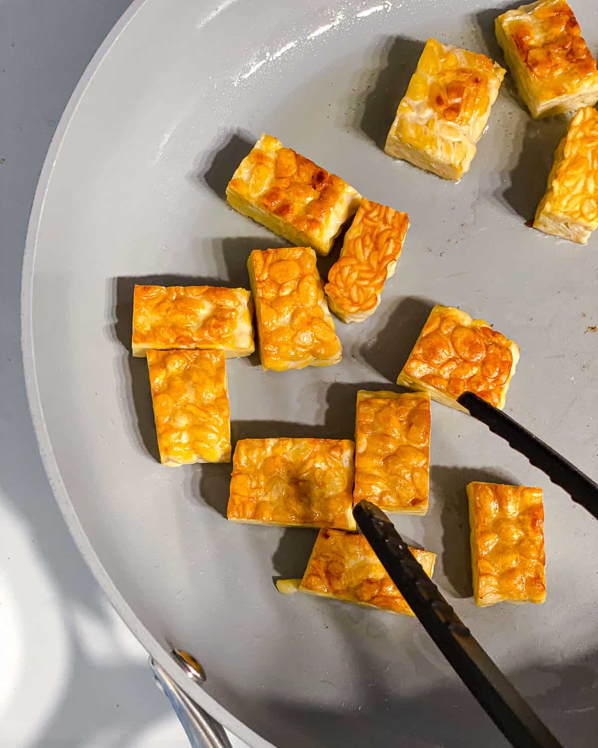 process shot of flipping tempeh in pan