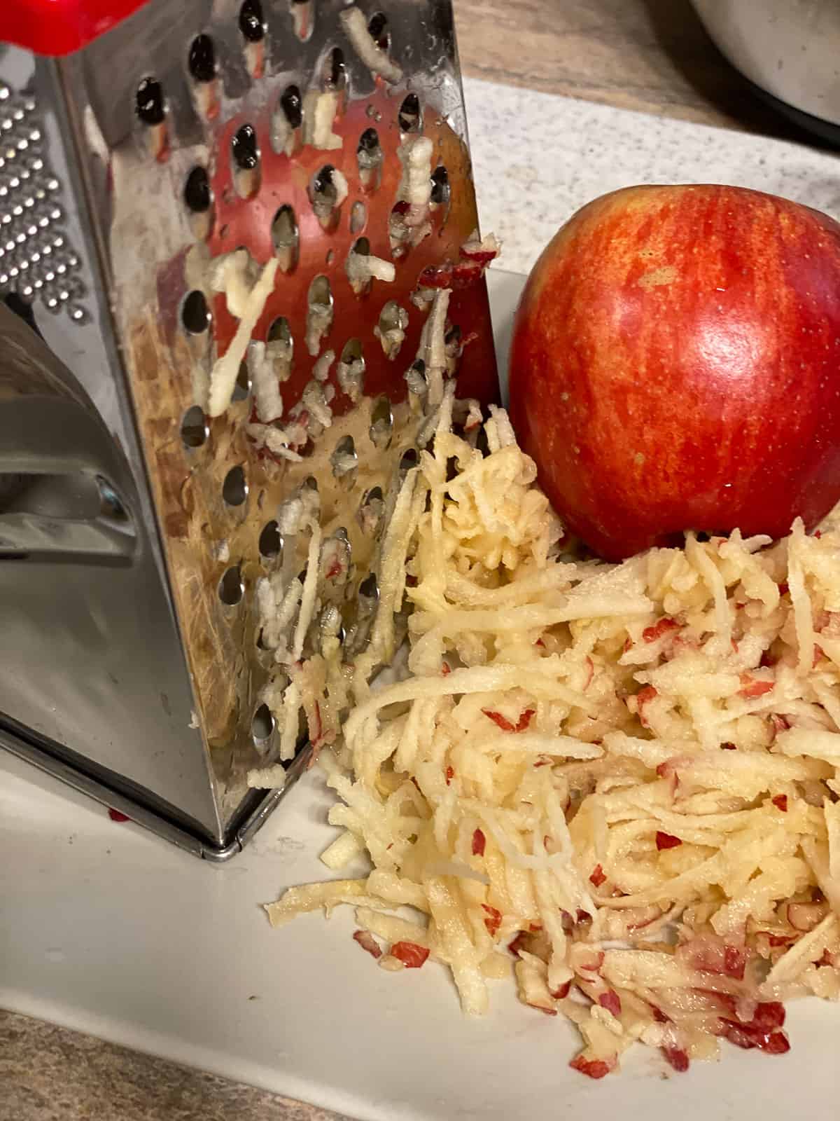 process shot of grating apples with apple in the background