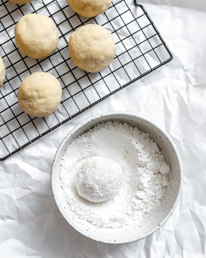 balls of dough alongside powdered sugar in bowl