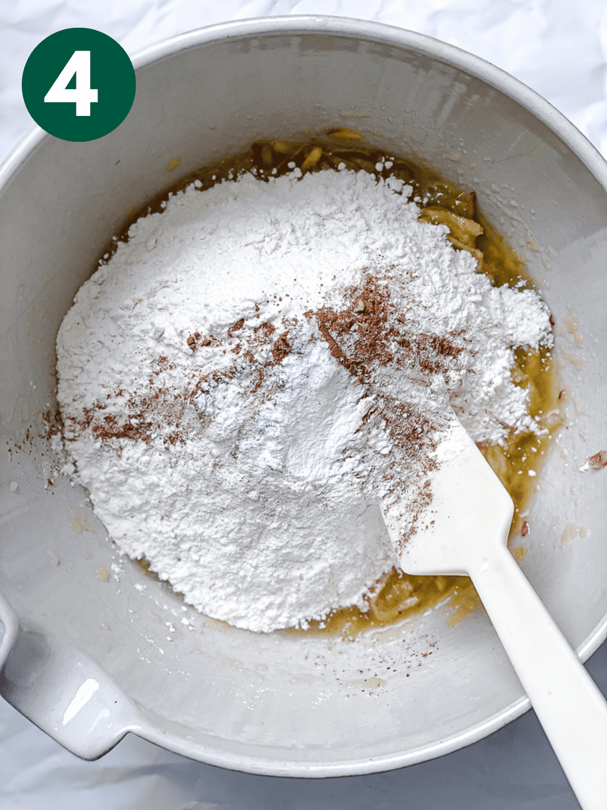 stirring the dry ingredients for apple cinnamon bread with a white spatula in a large white bowl.