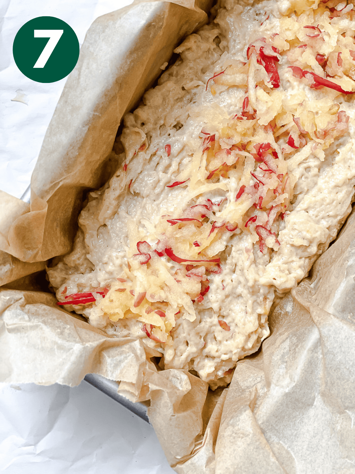 unbaked apple cinnamon bread topped with shredded apples in a loaf pan.