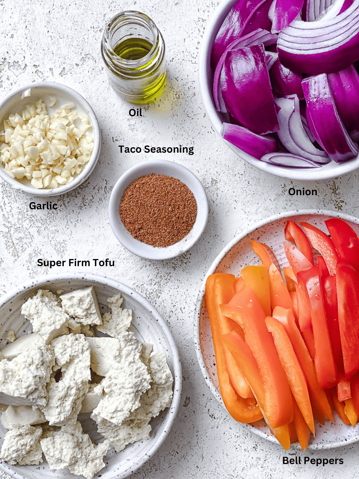 ingredients for tofu fajitas in individual white bowls with labels.