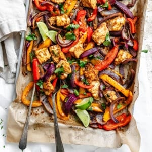 roasted taco-seasoned tofu chunks, onion, and bell peppers on a parchment-lined sheet pan.