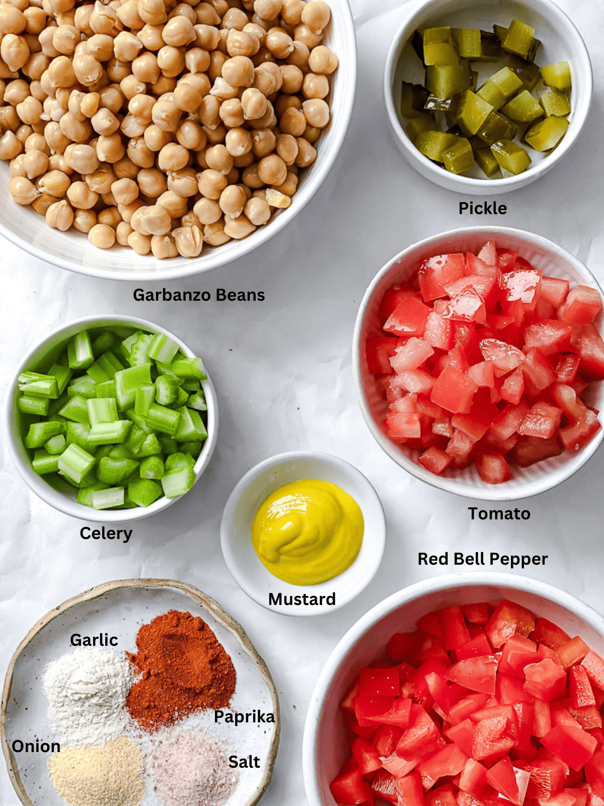 ingredients for vegan garbanzo bean salad in small white bowls with labels.