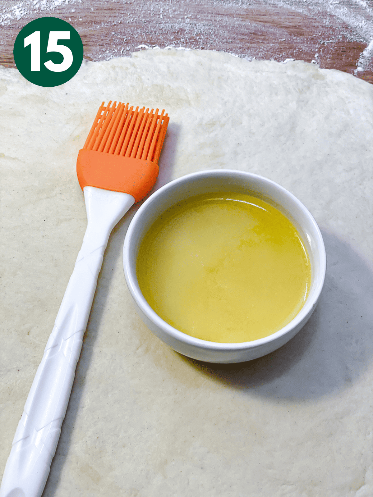 melted butter in a white bowl next to a pastry brush.