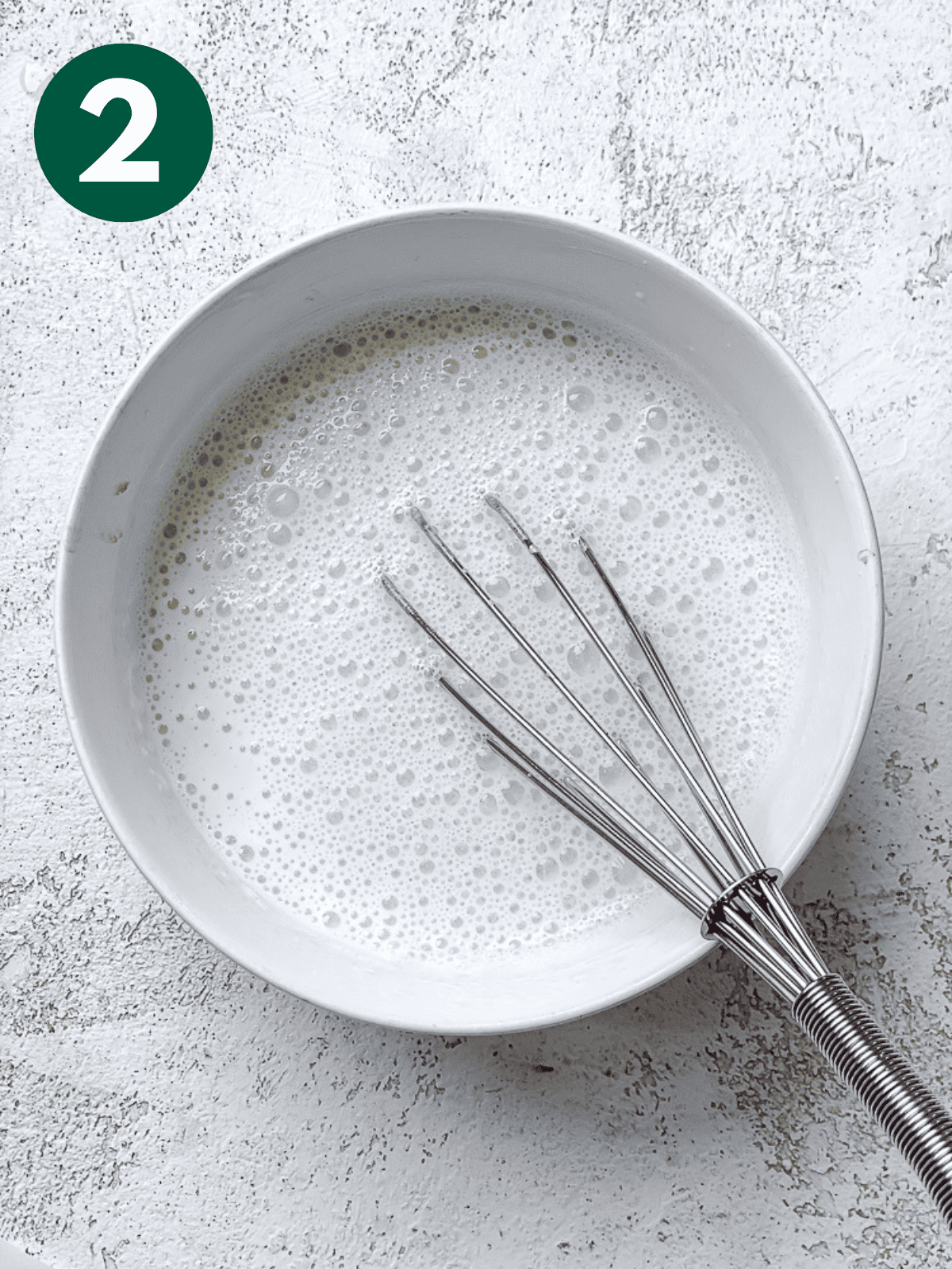 whisking vegan buttermilk in a white bowl.