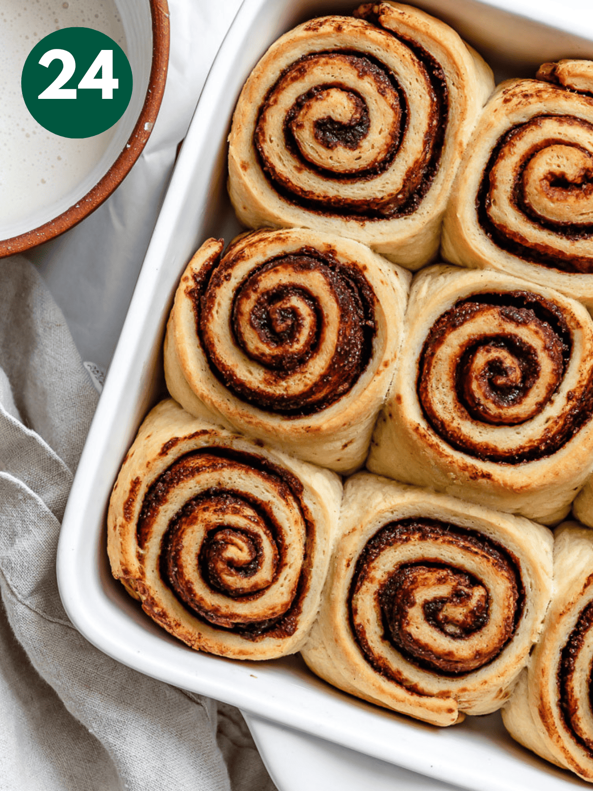 baked vegan cinnamon rolls in a white baking dish.