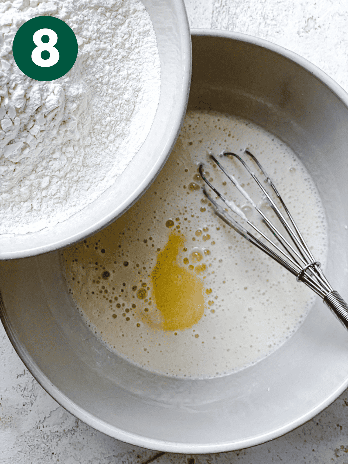 pouring flour into the wet mixture for vegan cinnamon roll dough.