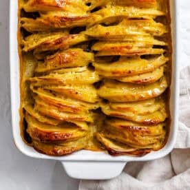 close up on baked Vegan Scalloped Potatoes in a white casserole dish.