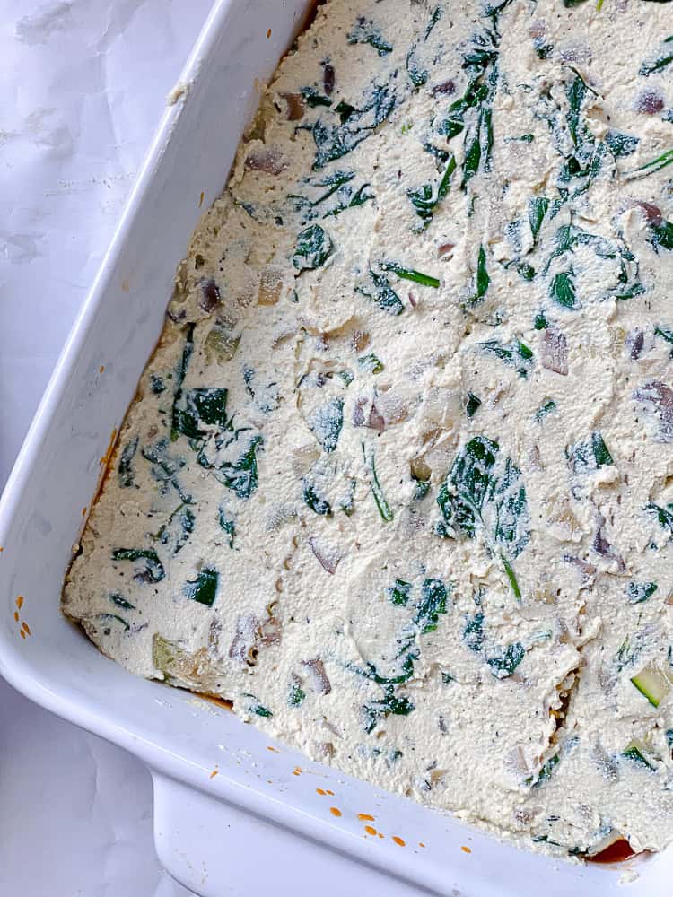 tofu ricotta spread over lasagna noodles in a baking dish.