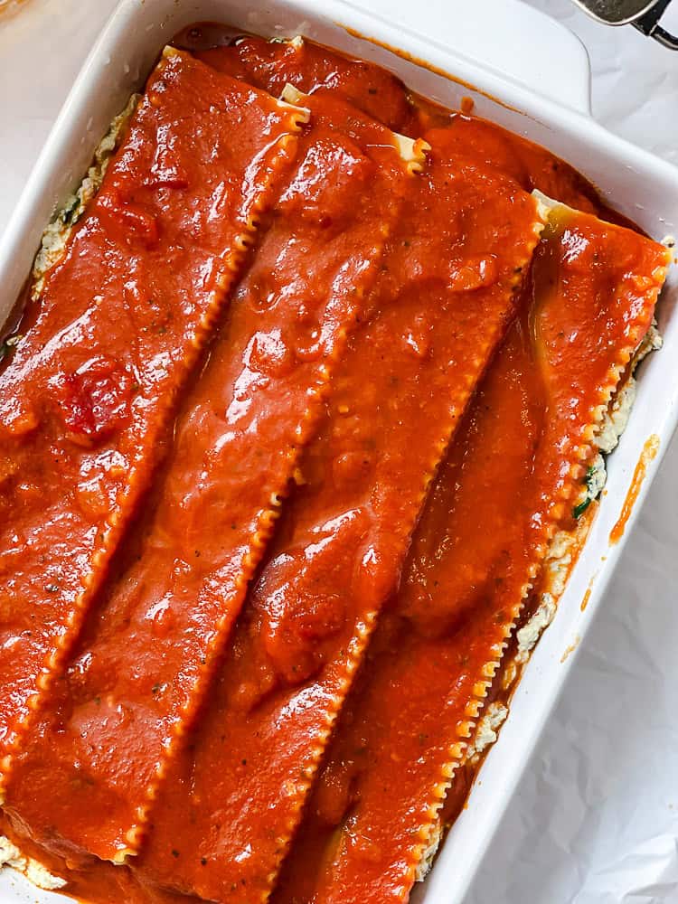 an assembled and unbaked vegan lasagna in a baking dish.