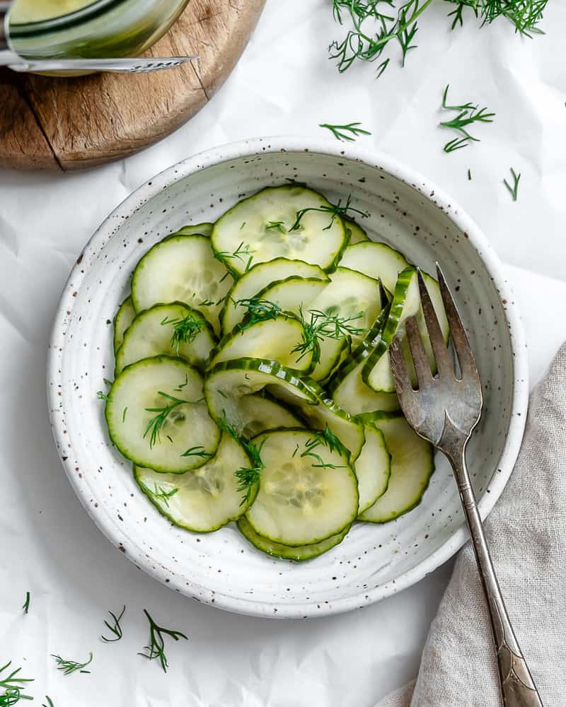 cucumber dill salad in a white bowl with a fork.