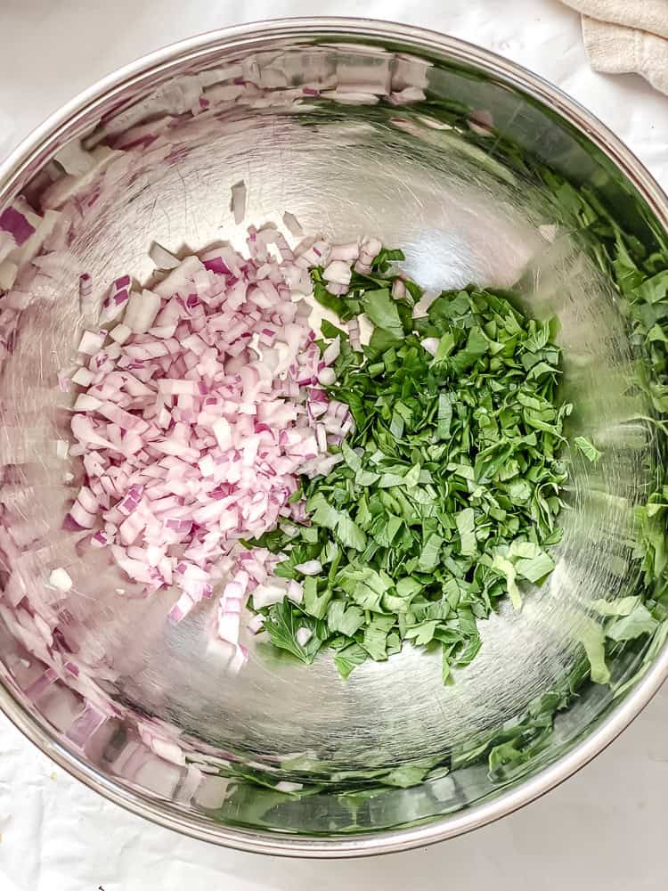 chopped red onion and parsley in a metal bowl.