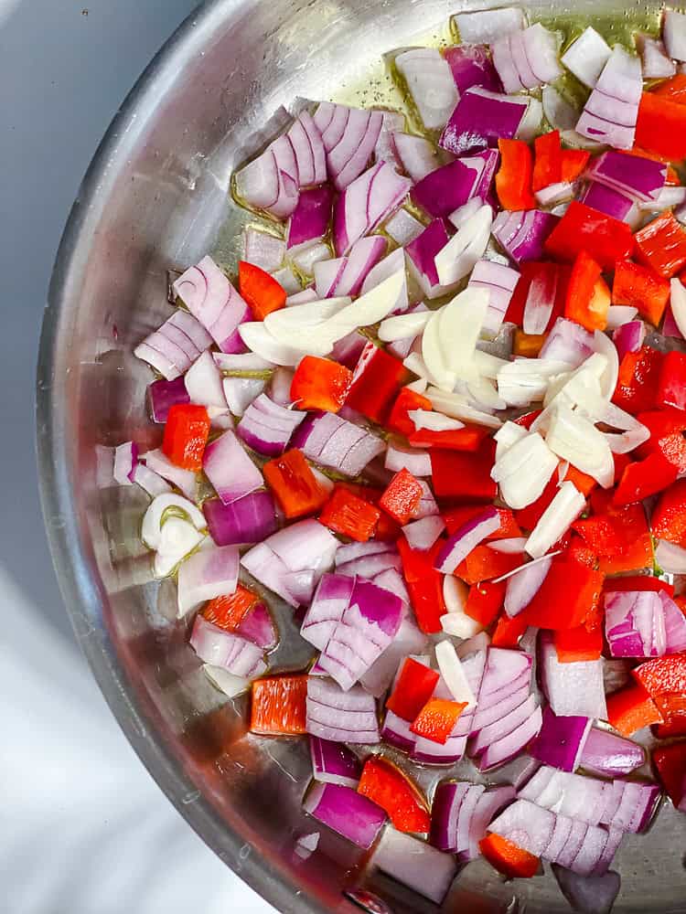 onion, garlic, and peppers cooking in a large pot.