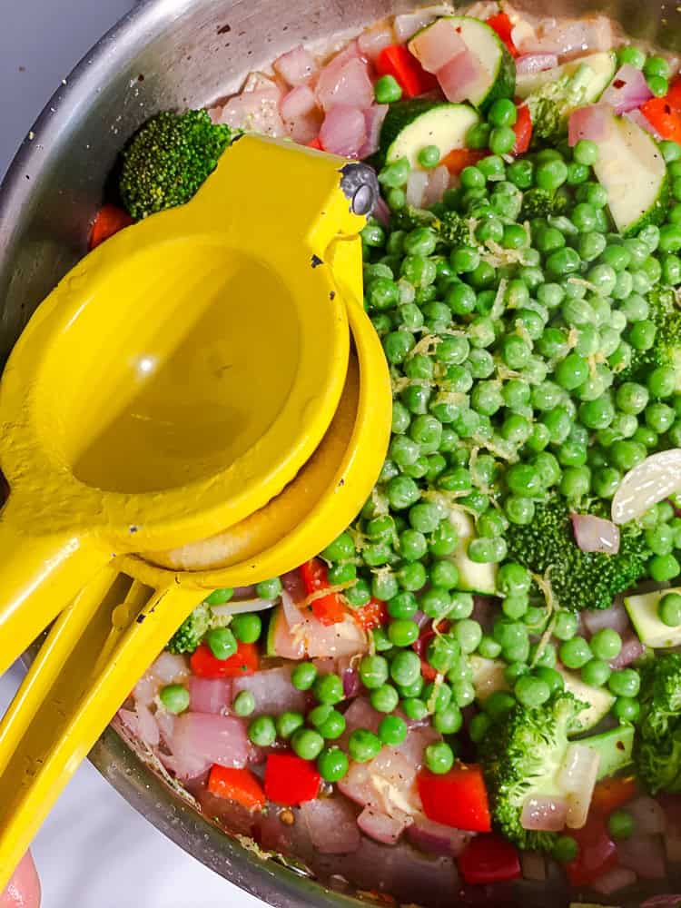 squeezing lemon juice into a pot full of vegetables.